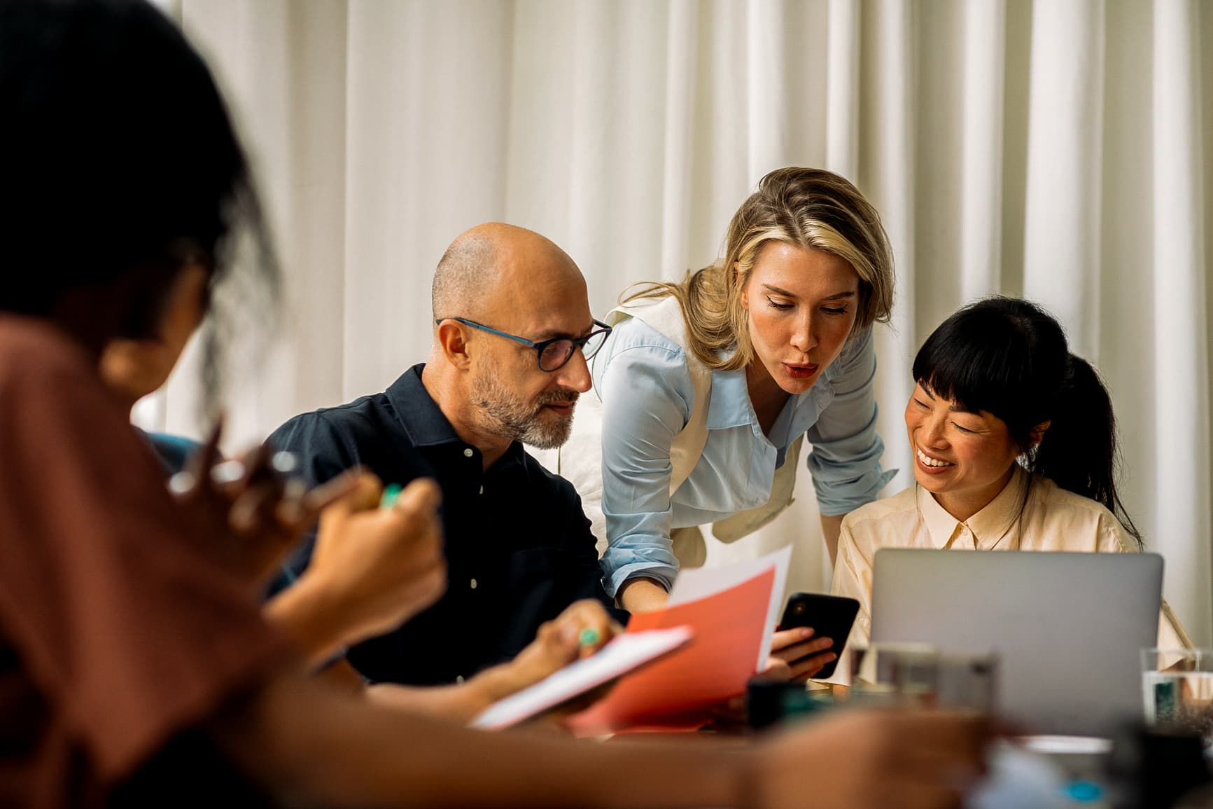 Woman showing some content on mobile phone to coworkers during office meeting
